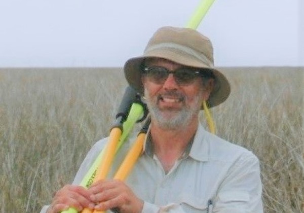 Professor Beland in the field holding measurement instruments. 