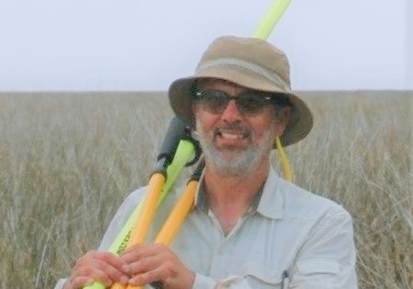 Professor Beland in the field holding measurement instruments.