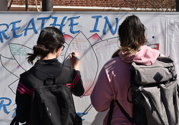 Two students standing, writing on a large board.
