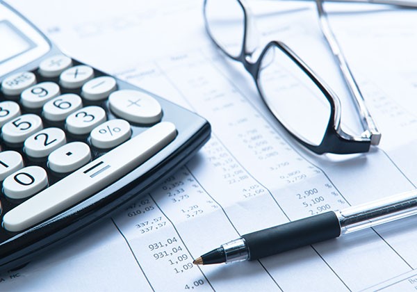 calculator and pen with glasses on desk