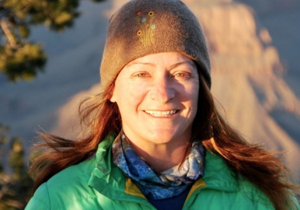 A medium blonde hair woman smiling with the sun reflected on her face.