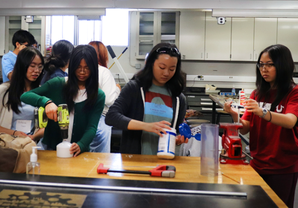 students gathered at lab table using tools on group activity