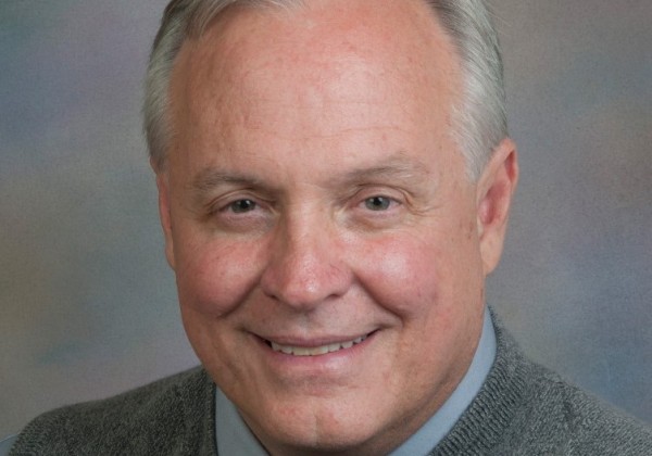 A portrait of a man with grey hair smiling. 