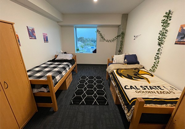 dorm room with two beds, desks and dressers.