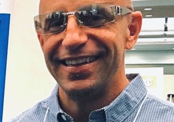 A man with glasses smiling at the camera. 