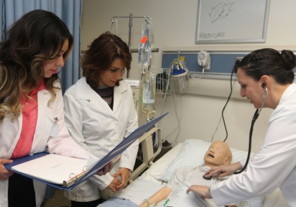 Master's students inspect a dummy patient in the Simulation Lab.