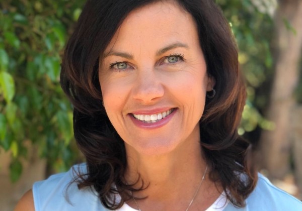 Portrait of a woman wearing light blue shirt smiling.
