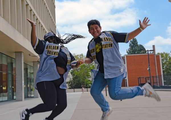 Two people wearing Orientation jerseys jumping in the air.
