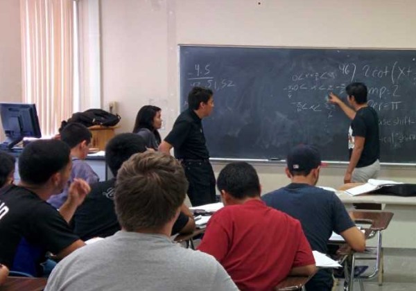 peer advisor with students writing on chalkboard