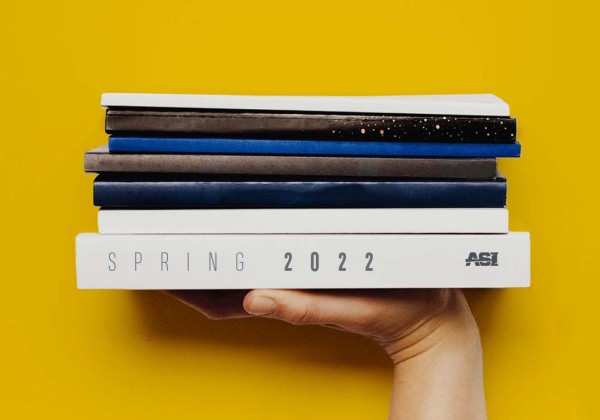 A hand holds up a stack of textbooks.