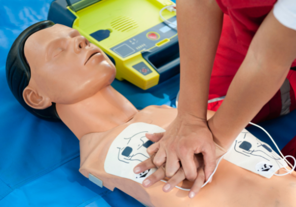 Person performing chest compressions on CPR mannequin 