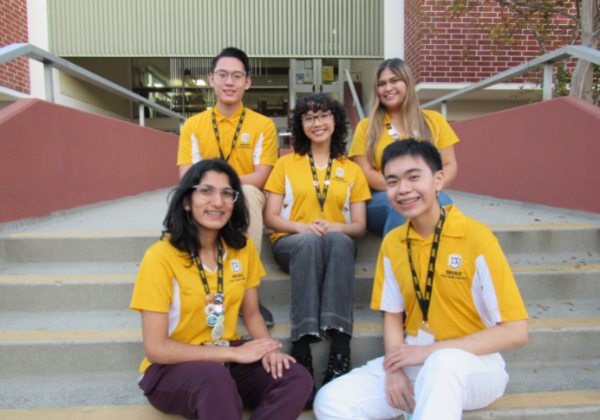 Five student peer health educators sitting on steps of Student Health Center