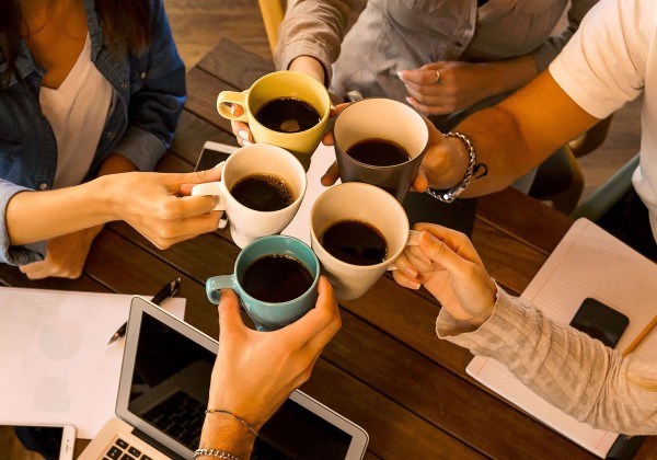Close-up of people toasting with coffee.