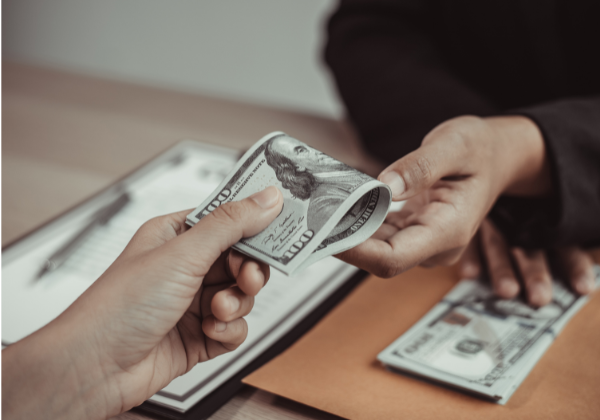 Hands crossing money across desk