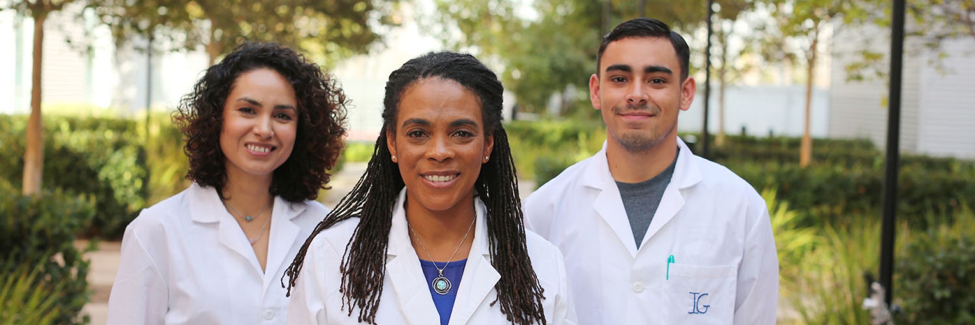 Students with White Lab Coats standing next to Dr. Foster in a courtyard