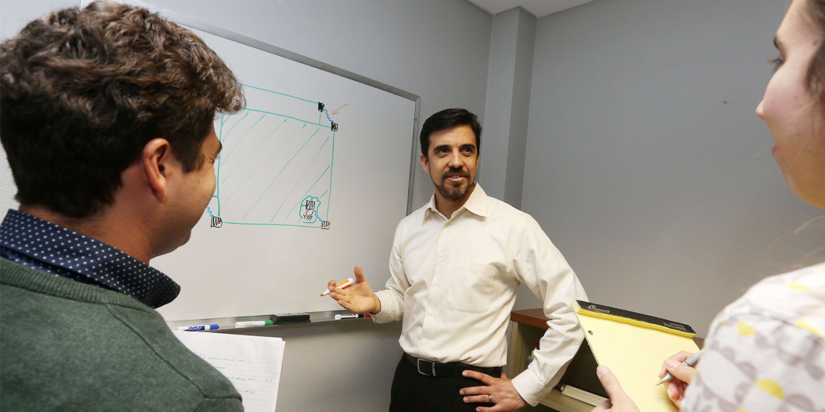 Professor Rodriguez by White Board as students take notes