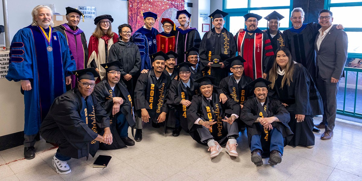 Inmates in graduation robes standing with professors