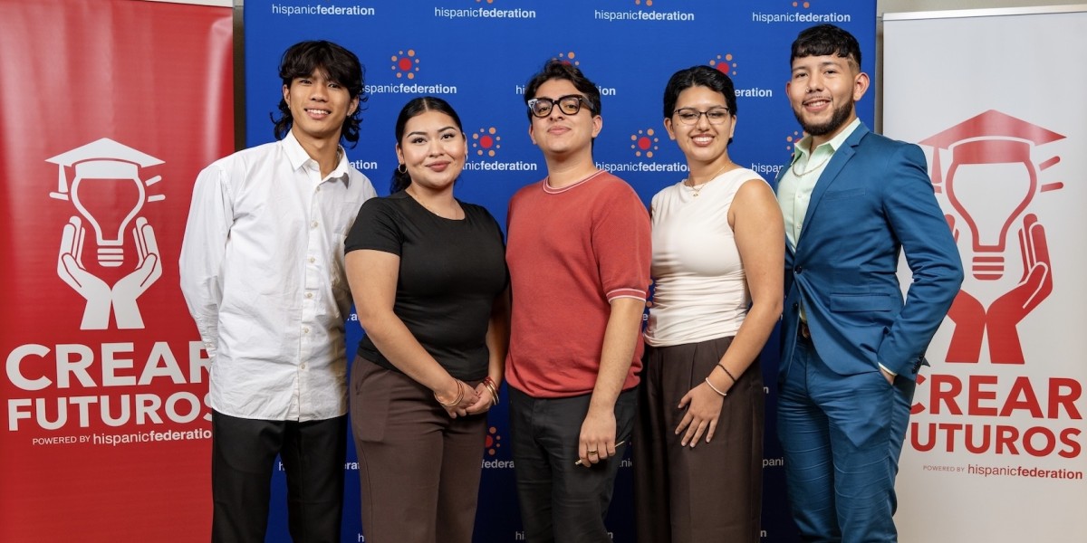 CREAR Futuros team smile together in front of a Hispanic Federation backdrop and CREAR Futuros banners