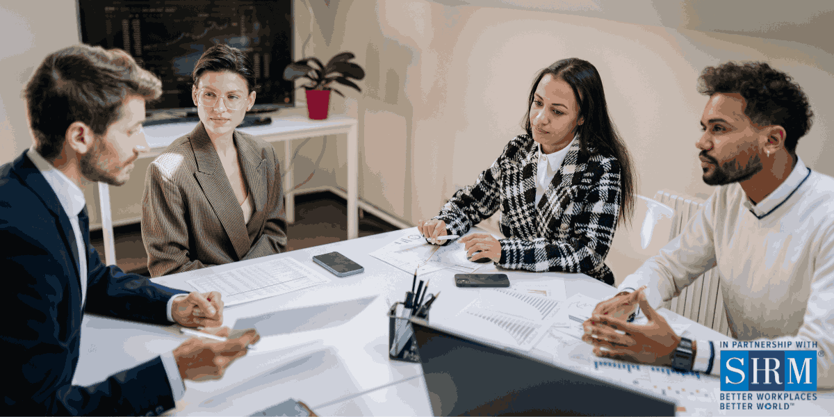 Four individuals sit around table. They are interviewing a man who is wearing glasses and holding a document. SHRM logo.