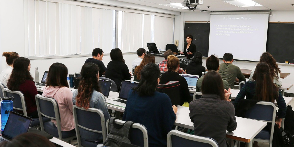 A professor giving a lecture to a large classroom full of students.