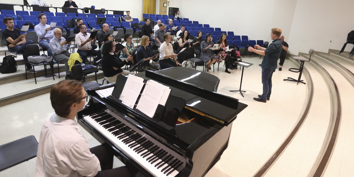 A music professor inside of a music hall giving a lecture to their students.