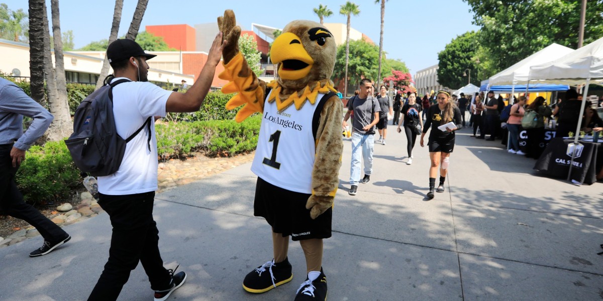 Eddie the Golden Eagle high-fiving a student on the Main Walkway.