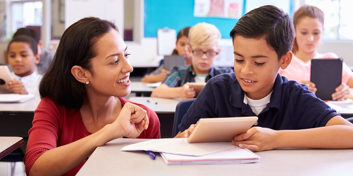 Female teacher and male student at desk.