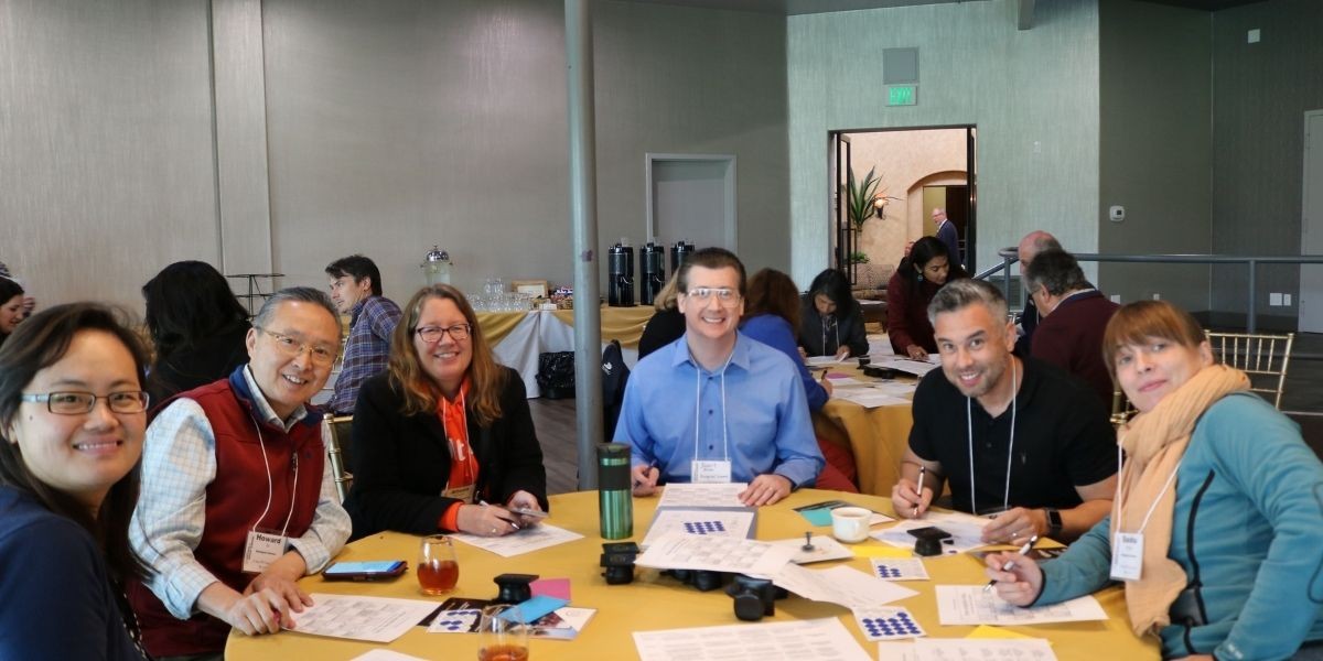 Male and female faculty members with names tags around a table smiling at camera