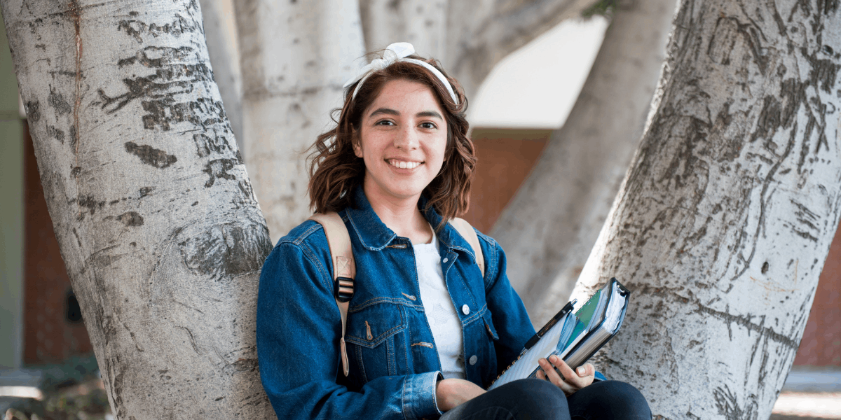 Female student with backpack and holding books.