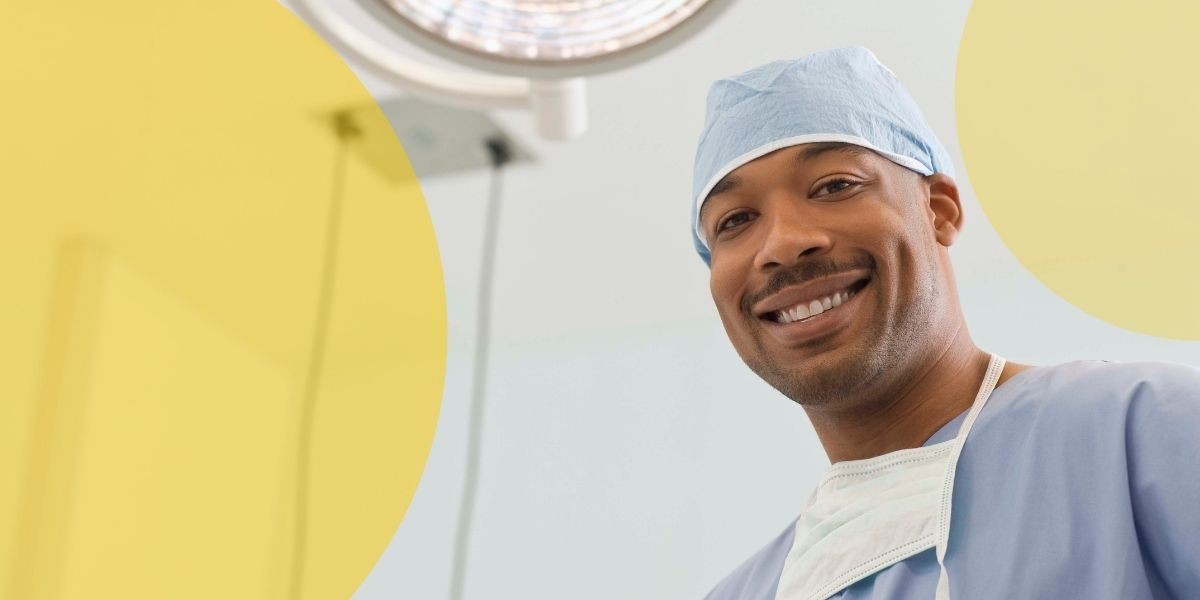 Black man with blue scrubs and a medical mask around his neck