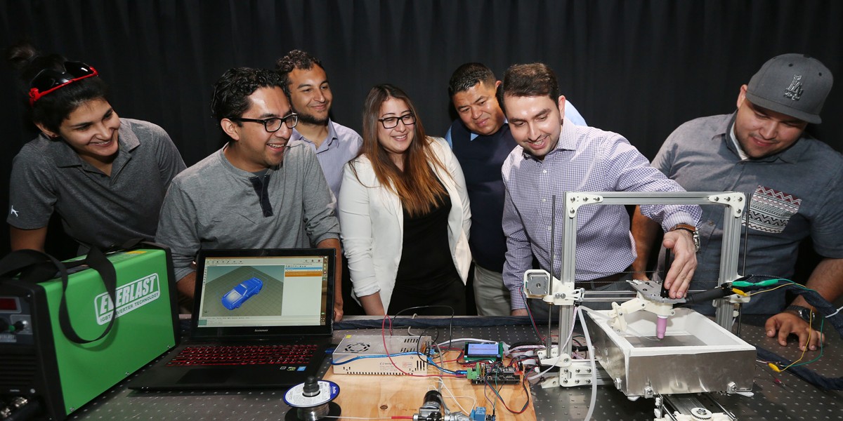 faculty and students work with 3d printer in lab