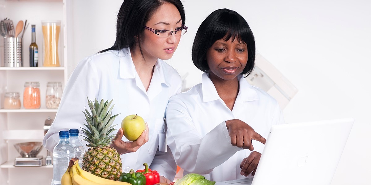 Two female nutritional scientists looking at lab results on a laptop.