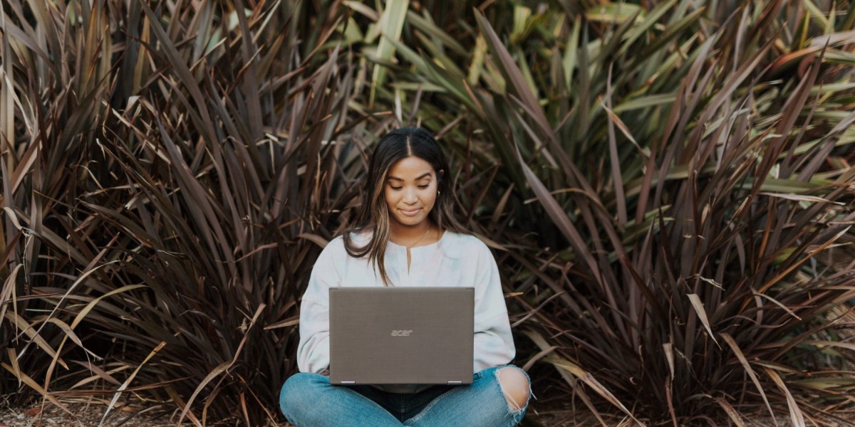 student typing on computer in park