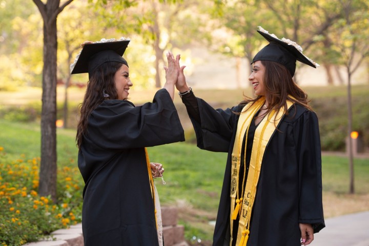 Two students at convocation giving each other a high five