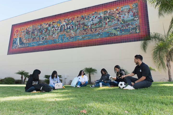 Students sitting on camps lawn in front of tile mosaic