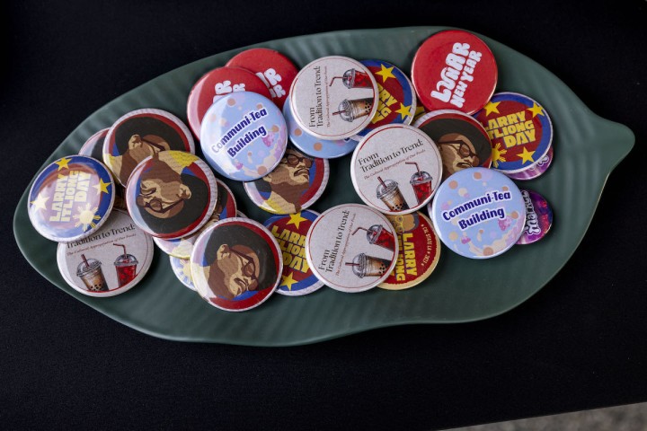 A tray filled with colorful round buttons featuring designs and text such as “Community Building” and illustrated drinks sits on a table.