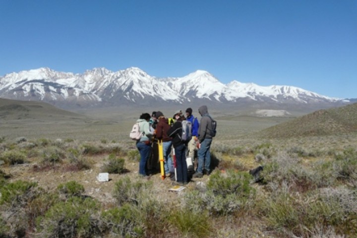 Group of students standing in a field with mountains in the background