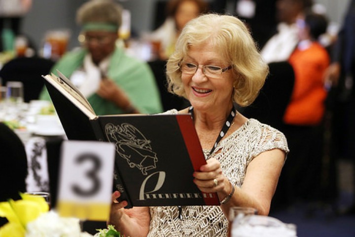 Female alumna opening a yearbook at a reception table