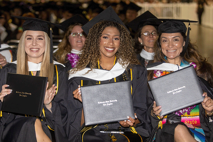 three graduates holding their diploma cover