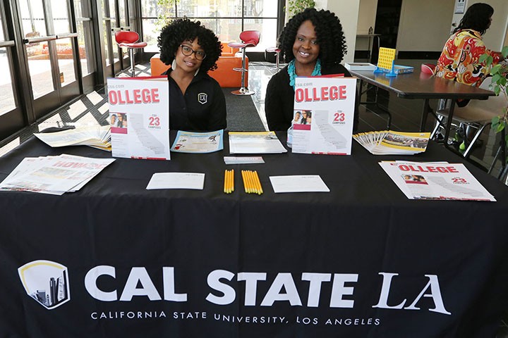 2 students sitting at a table promoting Cal State LA