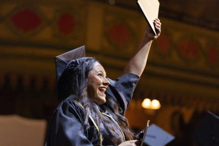 graduate holding up their diploma at ceremony