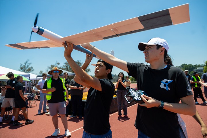 C3DPAC 2026 students hold UAV preparing to launch and point to sky