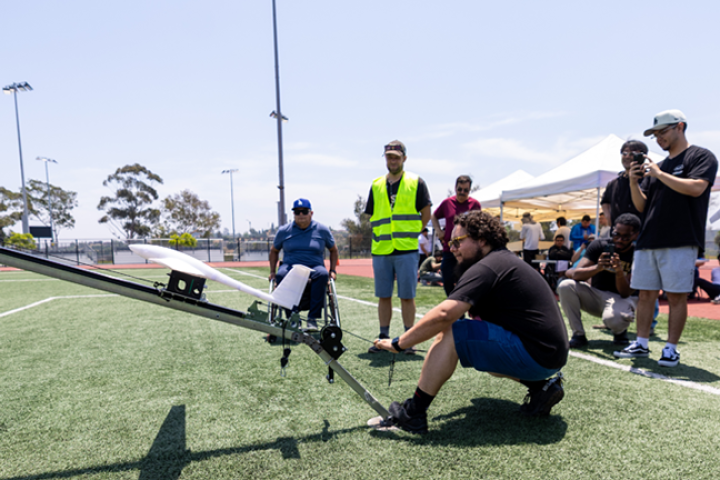 student launches uav on field near crowd