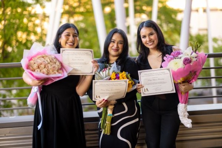 Three Students Holding Certificates and flowers