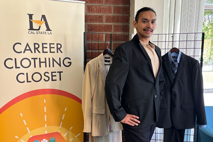 Student confidently wears professional suit and shoes in front of Career Clothing Closet display