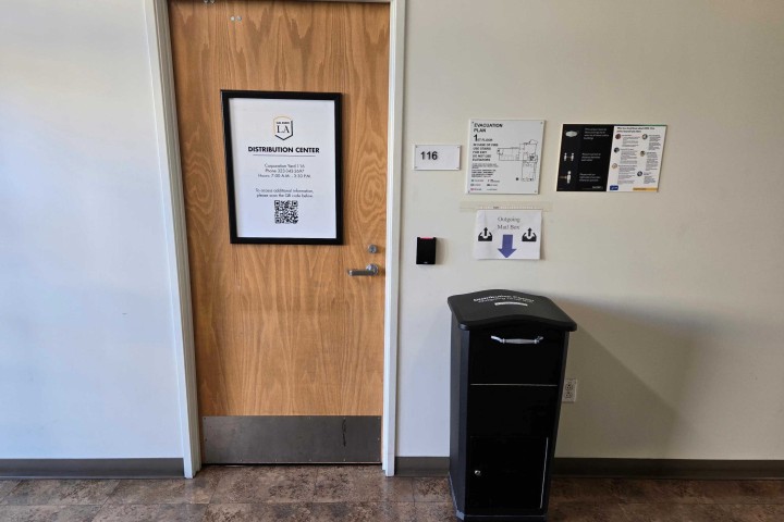 Door to the University Distribution Center with office sign and outgoing mail drop box nearby