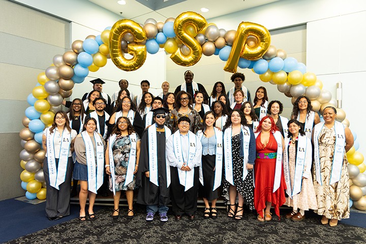 Large group of people wearing grad sashes and smiling.