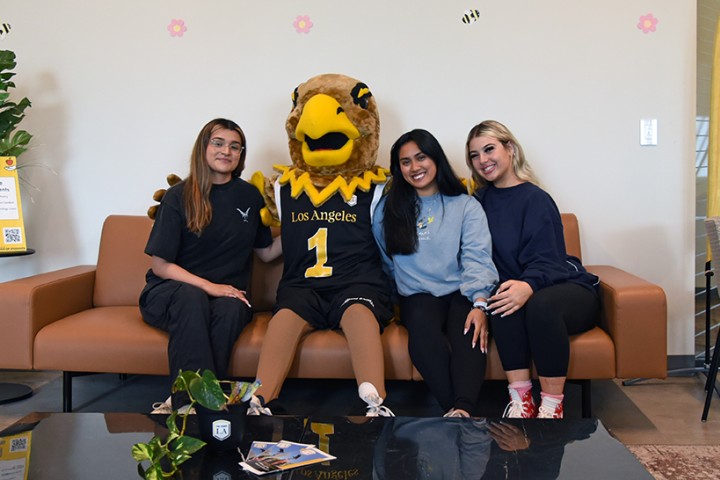 Eddie the Golden Eagle sitting on a couch with three student assistants.