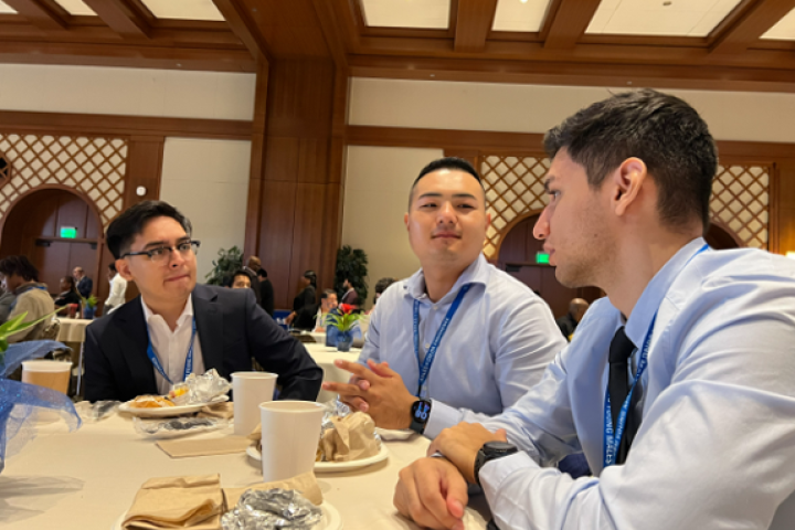 Three men in business attire talking at a table.