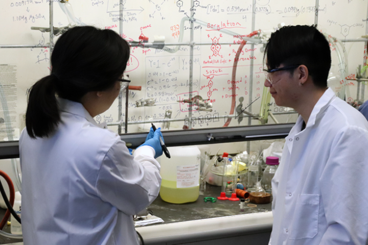 Dr Yangyan Lin works equation on glass with student